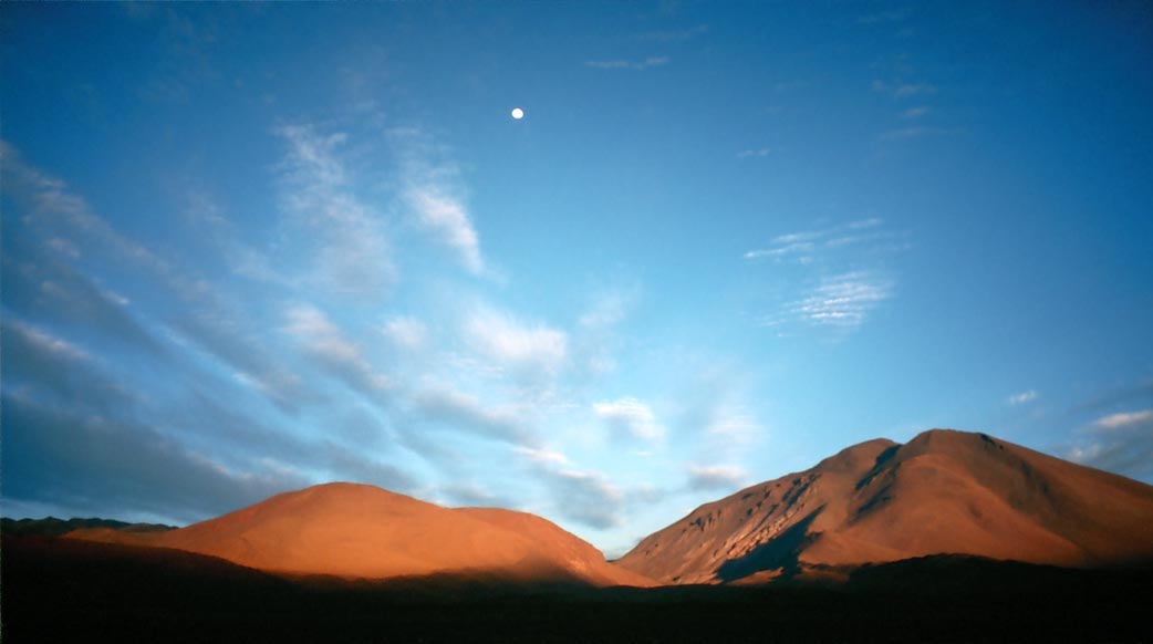 Wüstenlandschaft mit Bergen zwischen Tupiza und Uyuni mit untergehemdem Mond bei Sonnenaufgang