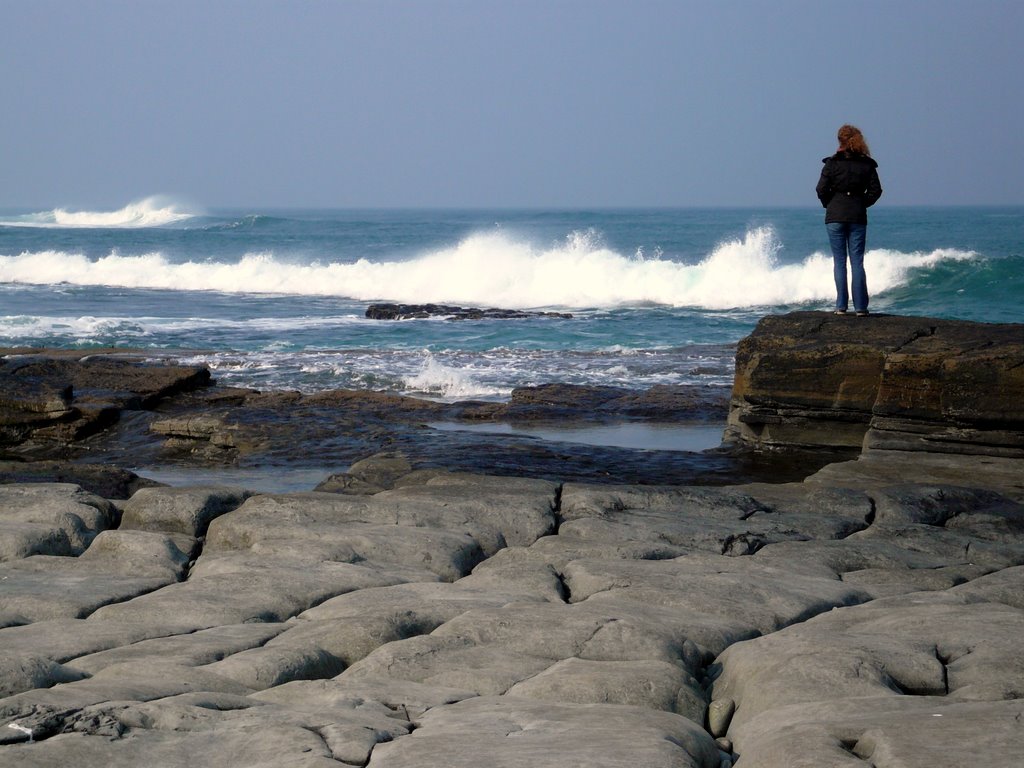 Gabi stands on a rock on the Atlantic coast and looks out at the waves.